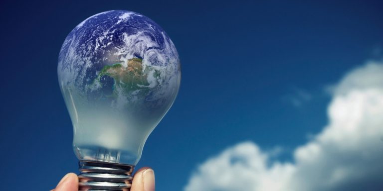 Lâmpada com espectro do planeta terra com plano de fundo um céu azul com nuvens simbolizando economia de energia elétrica e sustentabilidade