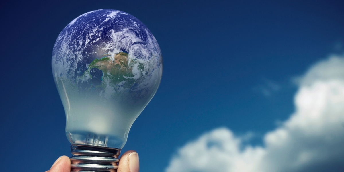 Lâmpada com espectro do planeta terra com plano de fundo um céu azul com nuvens simbolizando economia de energia elétrica e sustentabilidade